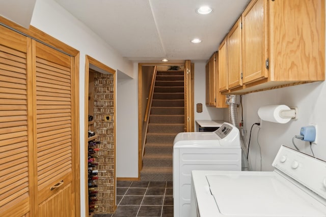 laundry area featuring washer and dryer, cabinets, and dark tile patterned flooring