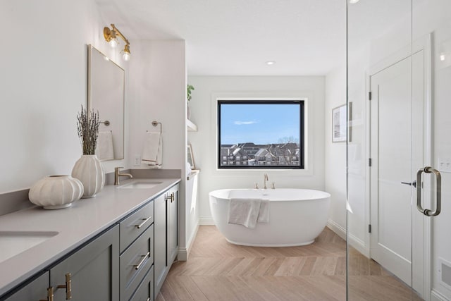 full bathroom featuring double vanity, a freestanding tub, a sink, and baseboards