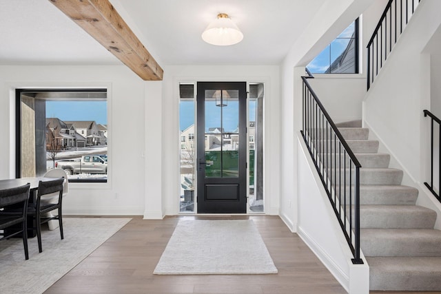 entrance foyer with a wealth of natural light, beam ceiling, baseboards, and wood finished floors