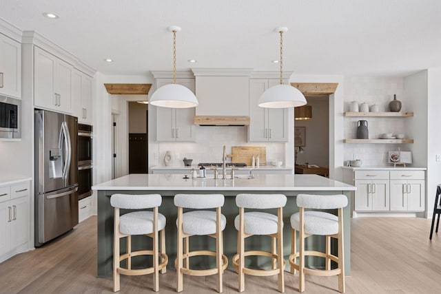 kitchen with light countertops, appliances with stainless steel finishes, light wood-style flooring, and decorative backsplash