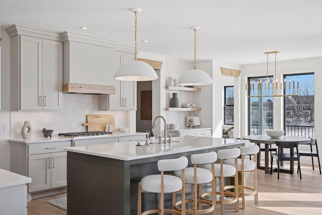 kitchen featuring stainless steel gas cooktop, light countertops, a sink, and backsplash