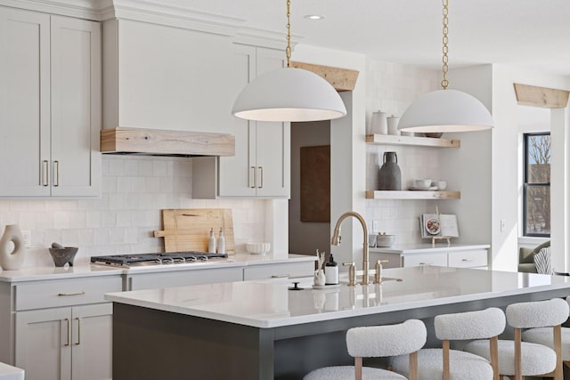 kitchen featuring a breakfast bar, stainless steel gas stovetop, open shelves, and a sink