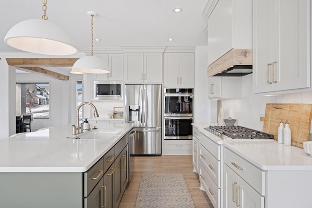 kitchen featuring stainless steel appliances, tasteful backsplash, light countertops, gray cabinetry, and a sink