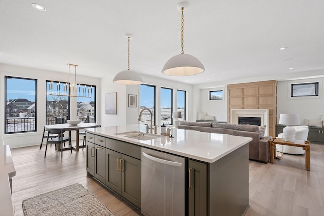 kitchen featuring a fireplace, light countertops, light wood-style flooring, a sink, and dishwasher