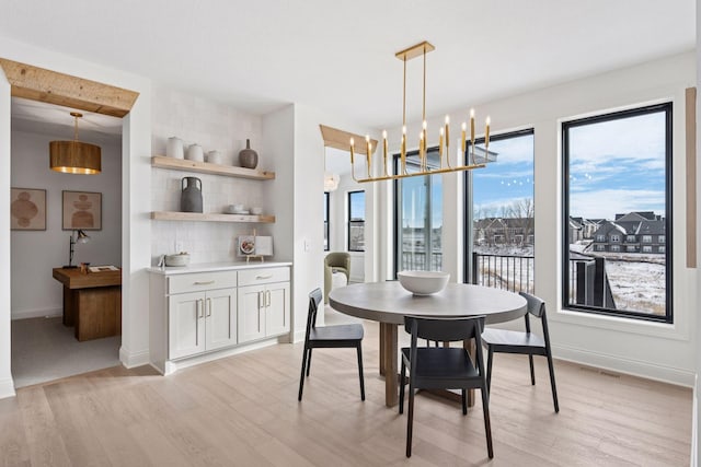 dining space with baseboards, a chandelier, visible vents, and light wood-style floors