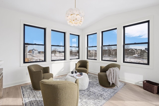 sitting room with baseboards, vaulted ceiling, wood finished floors, and a chandelier