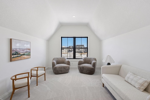 living area with lofted ceiling, baseboards, a textured ceiling, and carpet