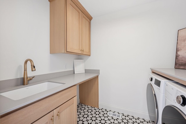 laundry area featuring cabinet space, baseboards, tile patterned floors, washer and dryer, and a sink