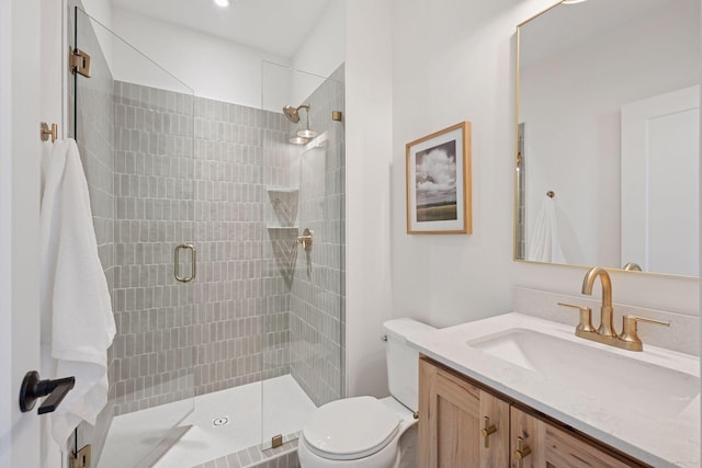 bathroom with vanity, a shower stall, and toilet