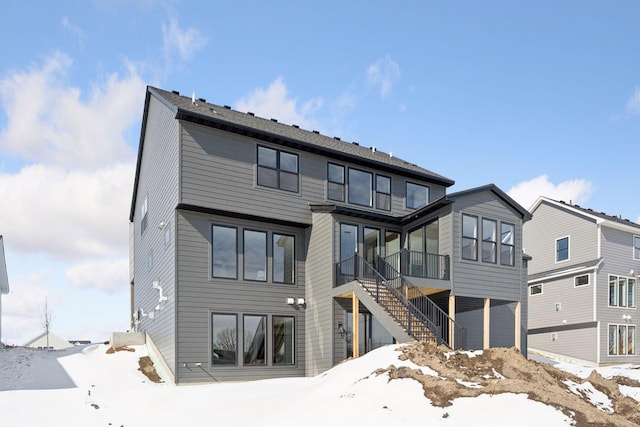 snow covered house featuring stairway