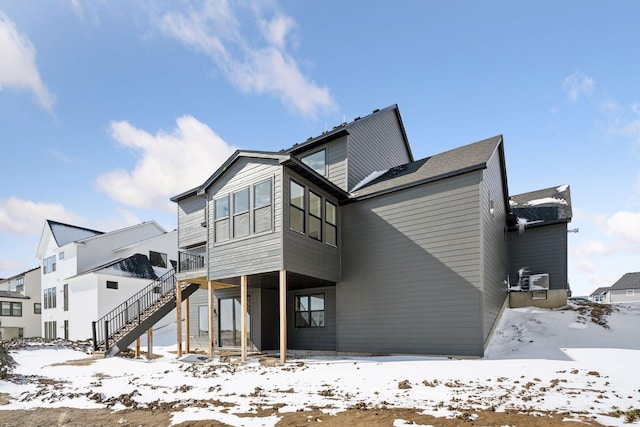 snow covered back of property featuring stairway