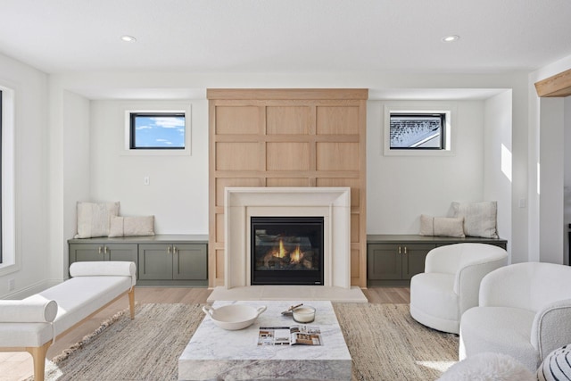 living room featuring recessed lighting, light wood-style flooring, and a glass covered fireplace