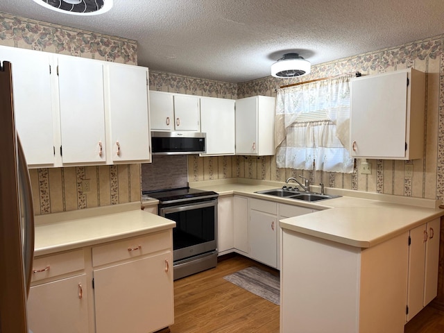 2402 Kenwood Dr SW, Willmar, MN 56201 - kitchen featuring appliances with stainless steel finishes, wallpapered walls, light wood-style floors, light countertops, and a textured ceiling