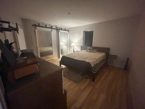 bedroom featuring hardwood / wood-style floors and a barn door