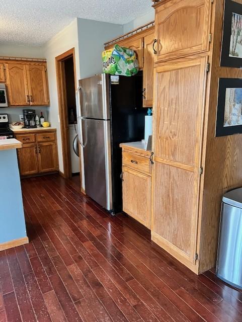 kitchen with washer / clothes dryer, dark wood-type flooring, white appliances, and a textured ceiling