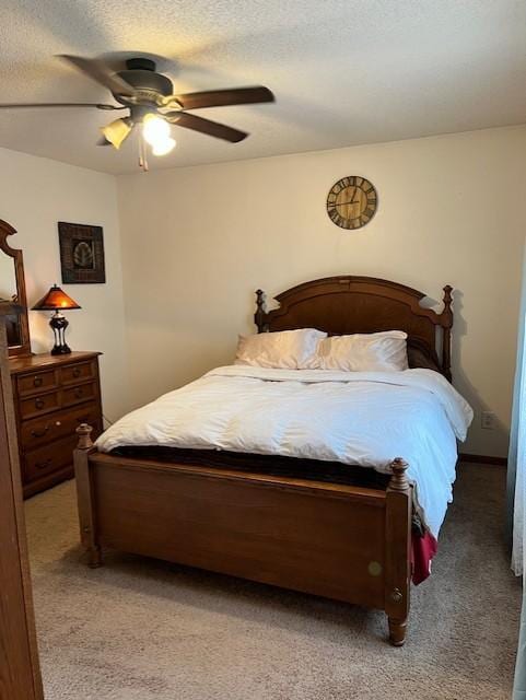 bedroom with ceiling fan, light colored carpet, and a textured ceiling