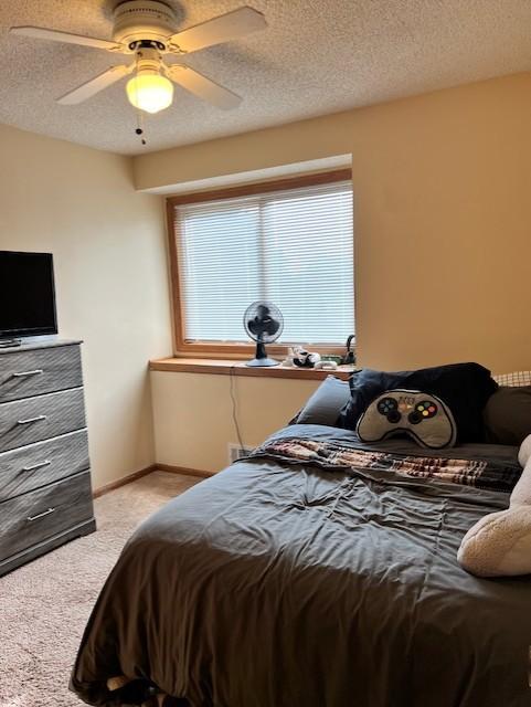 bedroom with ceiling fan, a textured ceiling, and light carpet