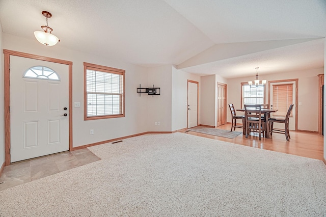 entrance foyer with a chandelier, vaulted ceiling, and light colored carpet