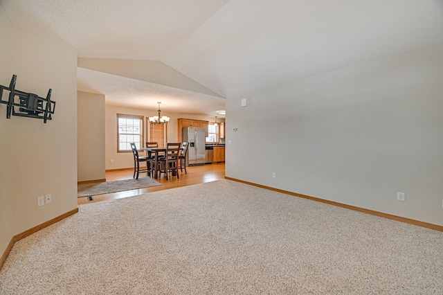 unfurnished living room featuring lofted ceiling, light carpet, and a notable chandelier