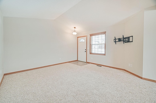 carpeted empty room featuring lofted ceiling