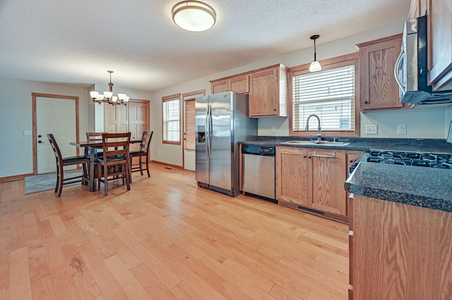 kitchen with appliances with stainless steel finishes, a notable chandelier, hanging light fixtures, and sink