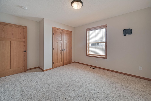 unfurnished bedroom featuring a textured ceiling, a closet, and light carpet