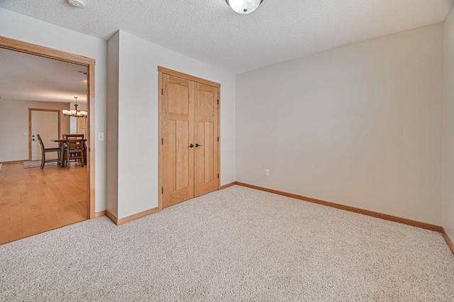 unfurnished bedroom with a closet, carpet floors, a chandelier, and a textured ceiling