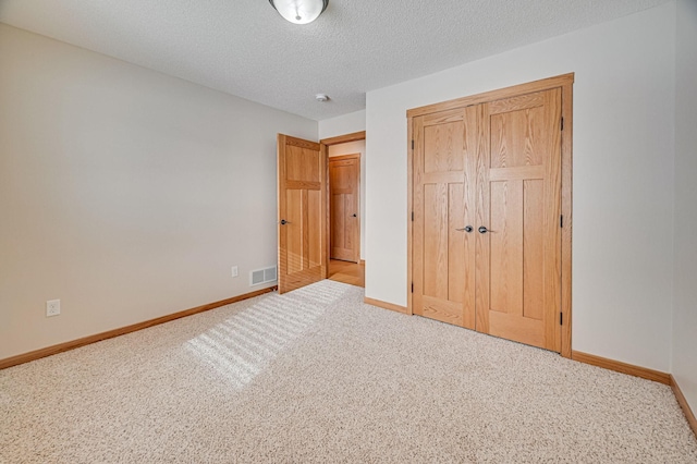 unfurnished bedroom featuring a textured ceiling and light carpet