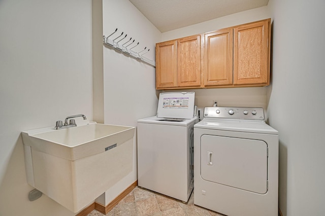 washroom featuring washing machine and dryer, cabinets, and sink