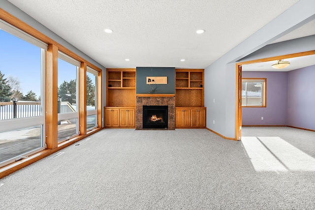 unfurnished living room featuring built in shelves, a textured ceiling, and light carpet