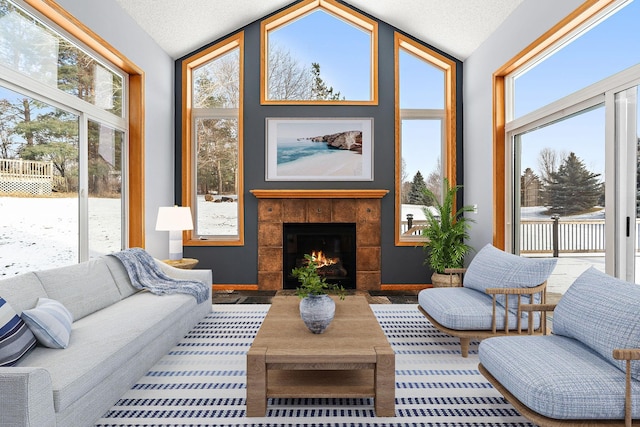 sunroom / solarium with a tiled fireplace, plenty of natural light, and lofted ceiling