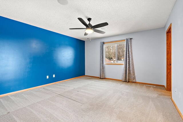 empty room featuring ceiling fan, light colored carpet, and a textured ceiling