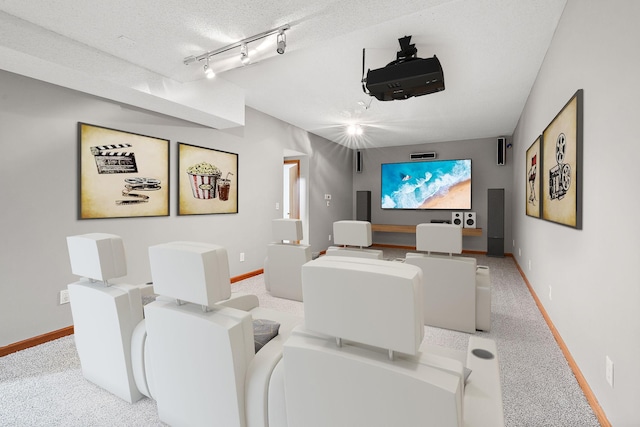 carpeted cinema room featuring rail lighting and a textured ceiling