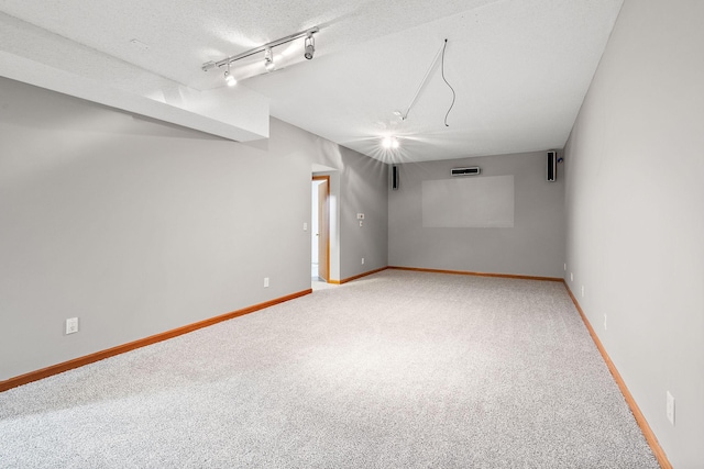 basement with carpet, rail lighting, and a textured ceiling