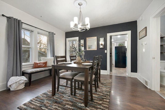 dining space with dark hardwood / wood-style floors and an inviting chandelier