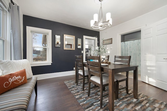 dining area featuring dark wood-type flooring and an inviting chandelier