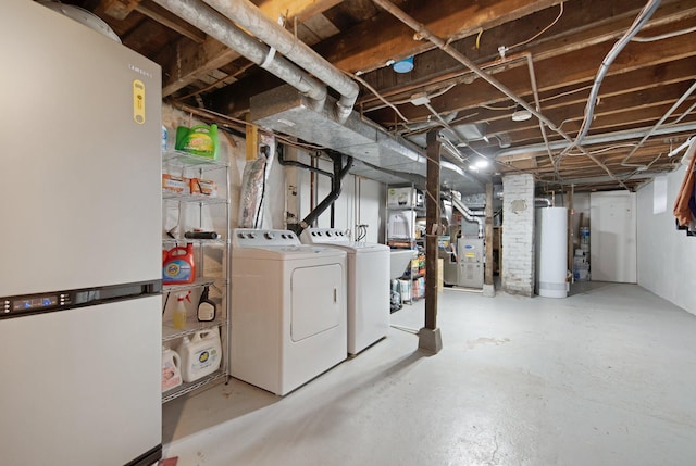 basement with washing machine and dryer, heating unit, white fridge, and gas water heater