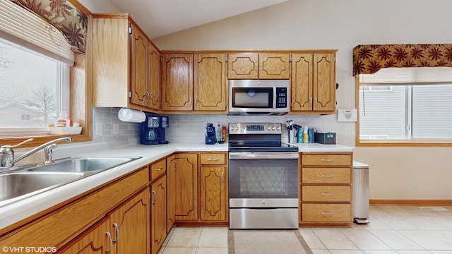 kitchen featuring appliances with stainless steel finishes, sink, tasteful backsplash, light tile patterned floors, and lofted ceiling