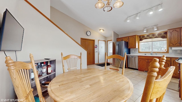 dining room with sink, a chandelier, light tile patterned floors, and lofted ceiling