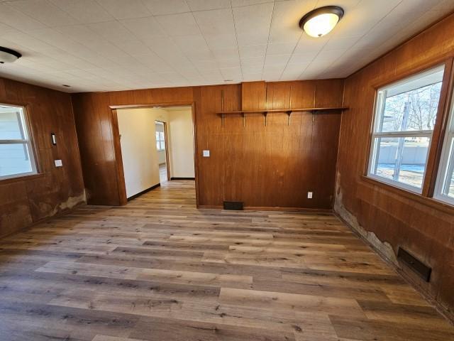 empty room with wooden walls and light wood-type flooring