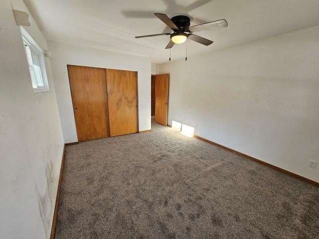 unfurnished bedroom with carpet flooring, a closet, and ceiling fan