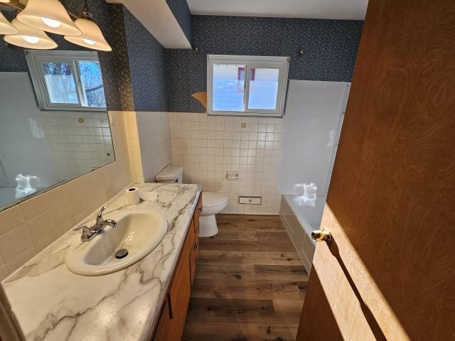 bathroom featuring hardwood / wood-style floors, vanity, toilet, and tile walls