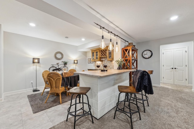 kitchen featuring a kitchen breakfast bar, light countertops, tasteful backsplash, glass insert cabinets, and pendant lighting