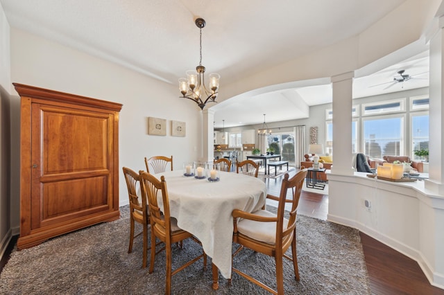 dining space with ornate columns, arched walkways, dark wood finished floors, and ceiling fan with notable chandelier