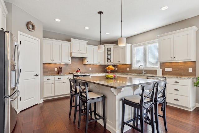 kitchen featuring white cabinets, a center island, stainless steel fridge, glass insert cabinets, and pendant lighting