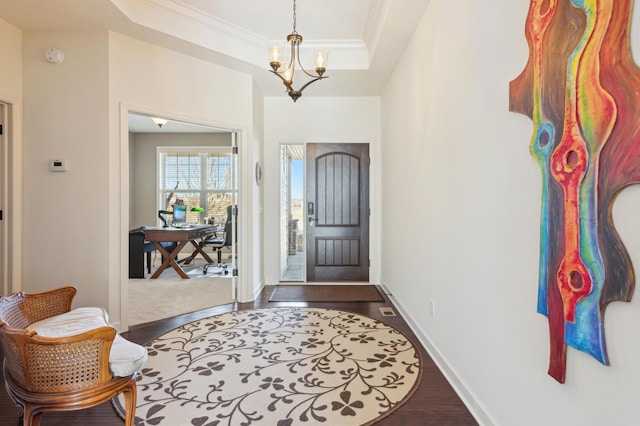 entryway featuring a chandelier, a raised ceiling, dark wood finished floors, and baseboards