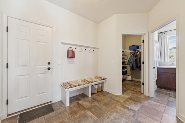 mudroom with a textured ceiling, stone finish floor, and baseboards