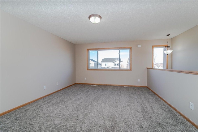 carpeted empty room featuring a textured ceiling