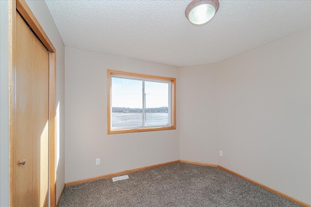 carpeted empty room featuring a textured ceiling