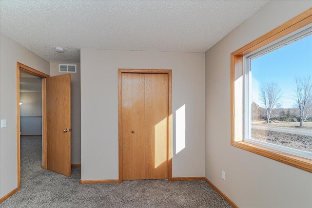 unfurnished bedroom with light carpet, a textured ceiling, and a closet